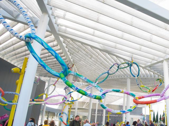 Colorful chain links hang from a perforated metal pergola outside the Manetti Shrem Museum at UC Davis.